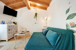 Ein Schlafzimmer mit einem Bett, einem Schminktisch, einem Schreibtisch, einem Fernseher und einer Wandleuchte.