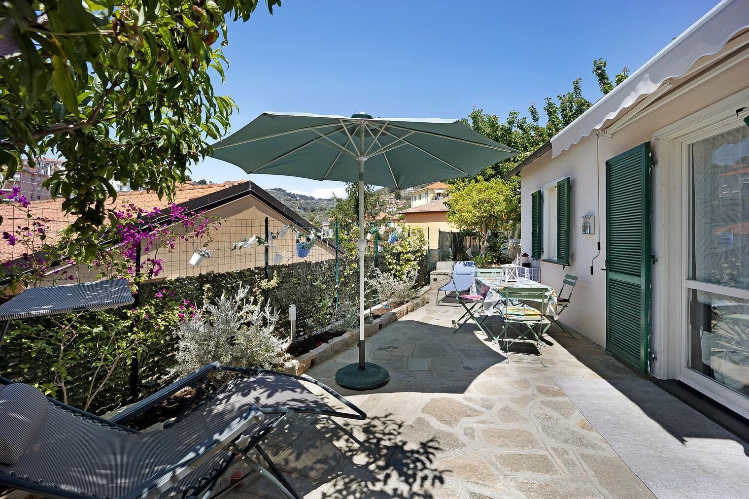 A patio with a table and chairs, a hanging chair, and an umbrella.