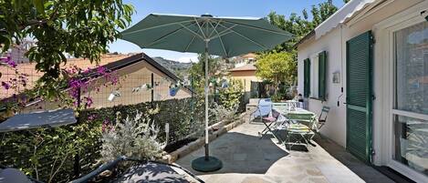 A patio with a table and chairs, a hanging chair, and an umbrella.