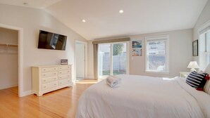 Una camera da letto con un letto grande, una cassettiera, una televisione e una porta vetrata scorrevole che dà su un balcone.