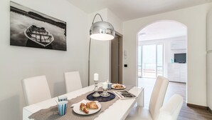 Un área de comedor con una mesa dispuesta para dos, un centro de mesa con velas y un cuadro en la pared.