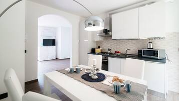 A modern kitchen with white cabinets, a microwave, and a dining area with a table set for two.