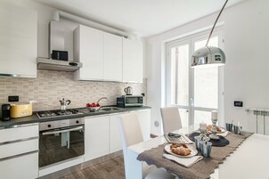 A modern kitchen with white cabinets, a gas stove, a microwave, and a coffee maker.