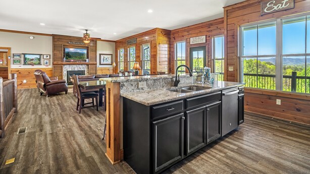 A spacious kitchen with a large island, wooden walls, and a dining area with a view.