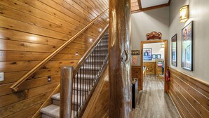 A wooden staircase with a handrail, a wooden wall with a light fixture, and a framed picture on the wall.