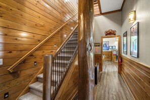 Staircase with a handrail and metal balusters, framed pictures, and a wall-mounted light fixture.