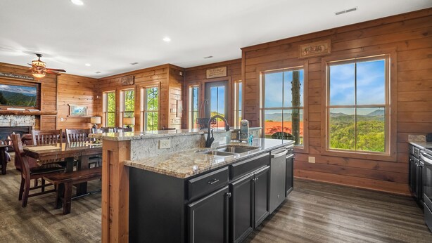 A spacious kitchen with wooden walls, large windows, and a granite countertop. - Angel’s Overlook | Hot Tub, Theater & Views – Sleeps 12 near Gatlinburg (Sevierville)