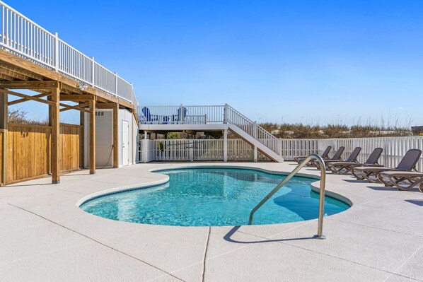 A pool area with a wooden deck, a white fence, and lounge chairs. - Kinlaw's Quarters- Ocean Isle Beach (Ocean Isle Beach)