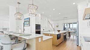 Una cocina moderna con armarios blancos, una isla central e iluminación colgante.