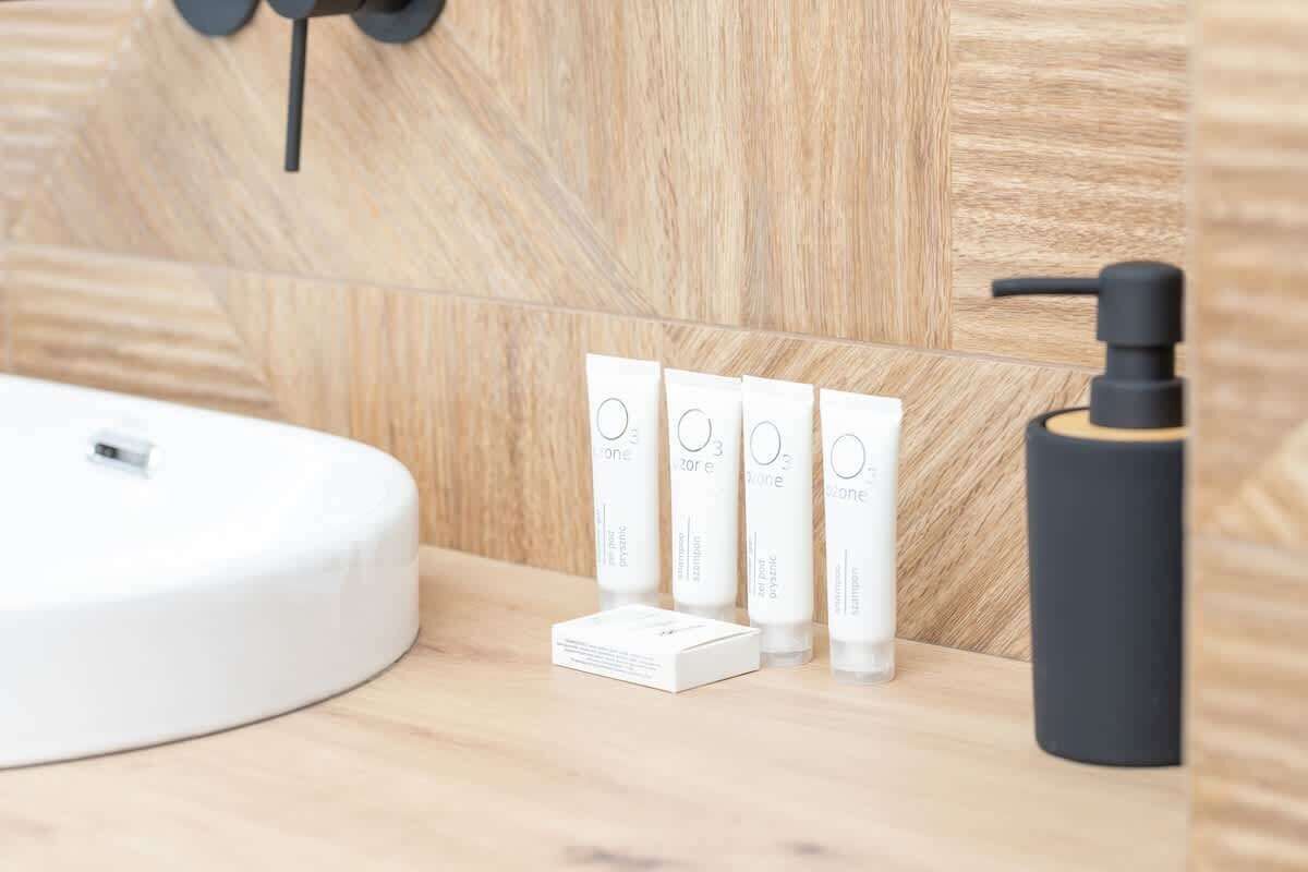 Minimal bathroom space with round sink, light wooden textures, stylish soap dispensers, and modern design.