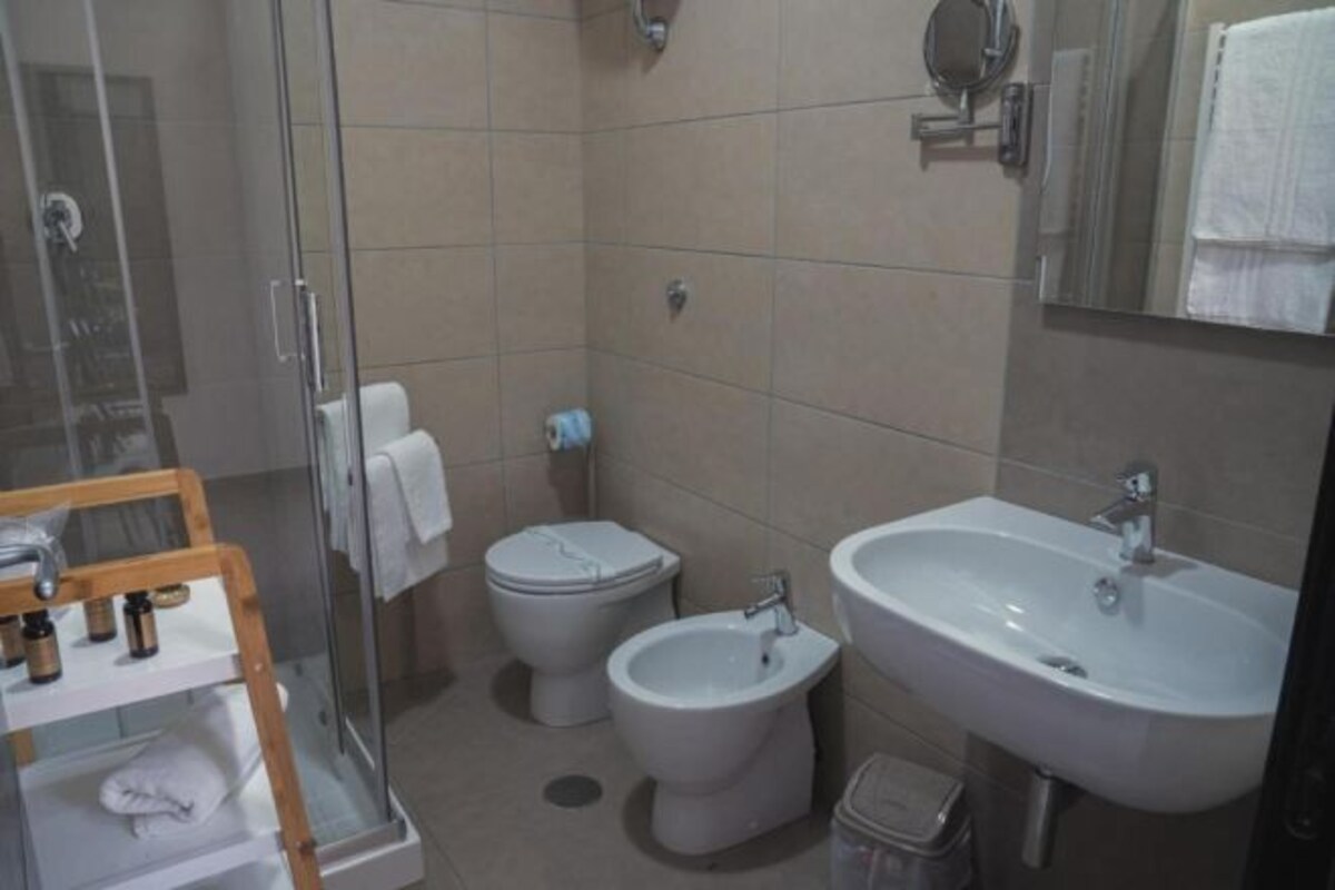A bathroom with a glass shower enclosure, a toilet, a bidet, and a sink.
