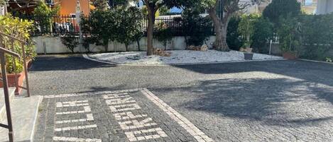 A paved area with a directional arrow and a tree in the center.