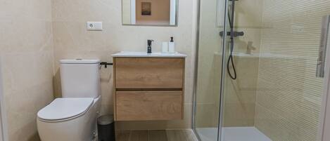 A modern bathroom with a toilet, sink, and shower.