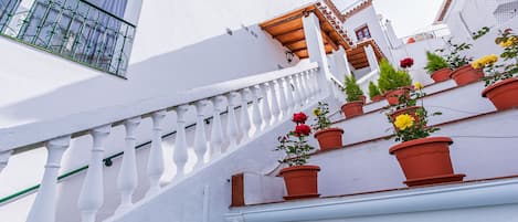 Um edifício branco com varanda e plantas em vasos.