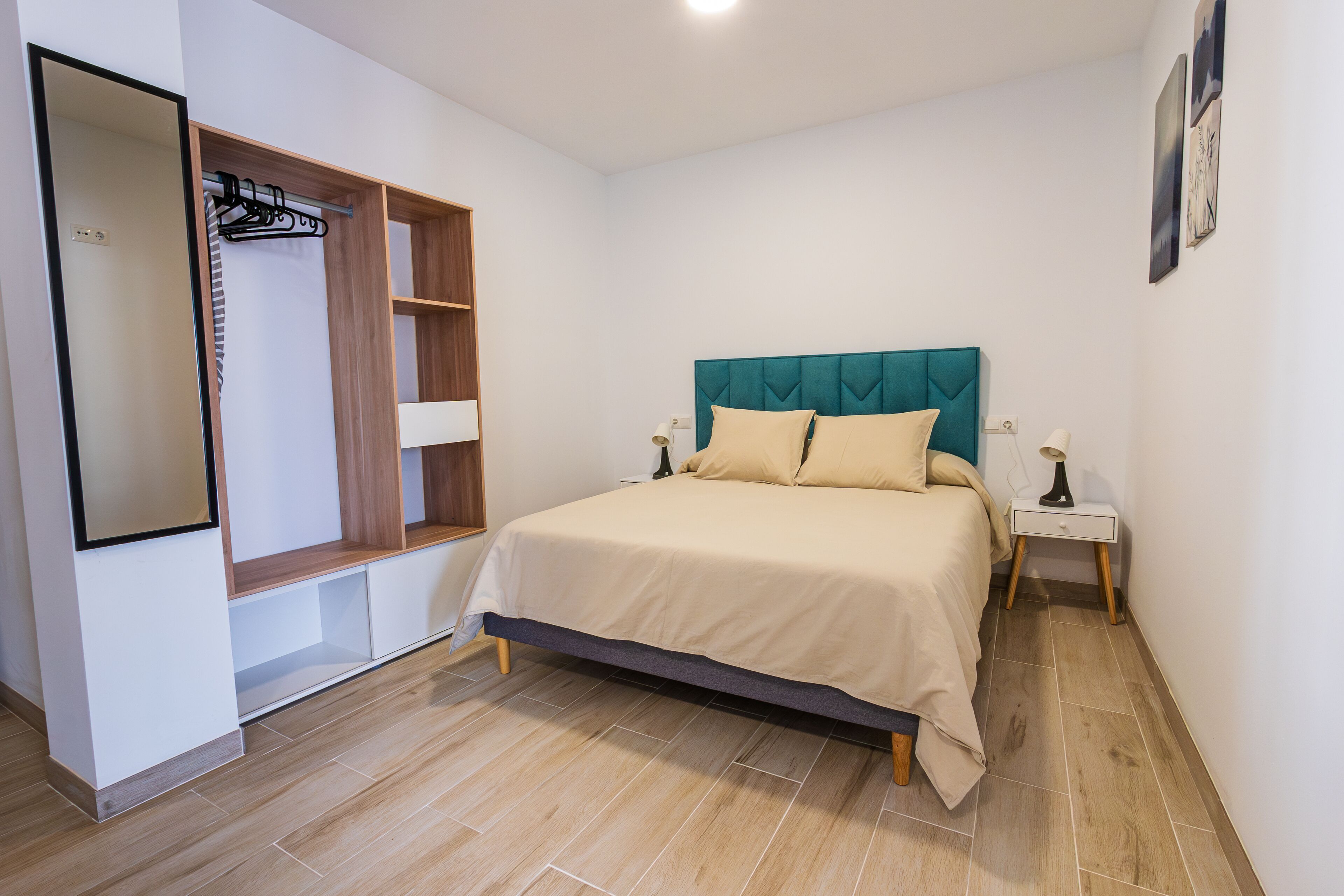 Un dormitorio con una cama, un armario, una mesita de noche y un espejo.