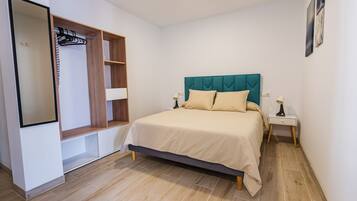 A bedroom with a bed, a wardrobe, a nightstand, and a mirror.