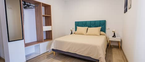 A bedroom with a bed, a wardrobe, a nightstand, and a mirror.