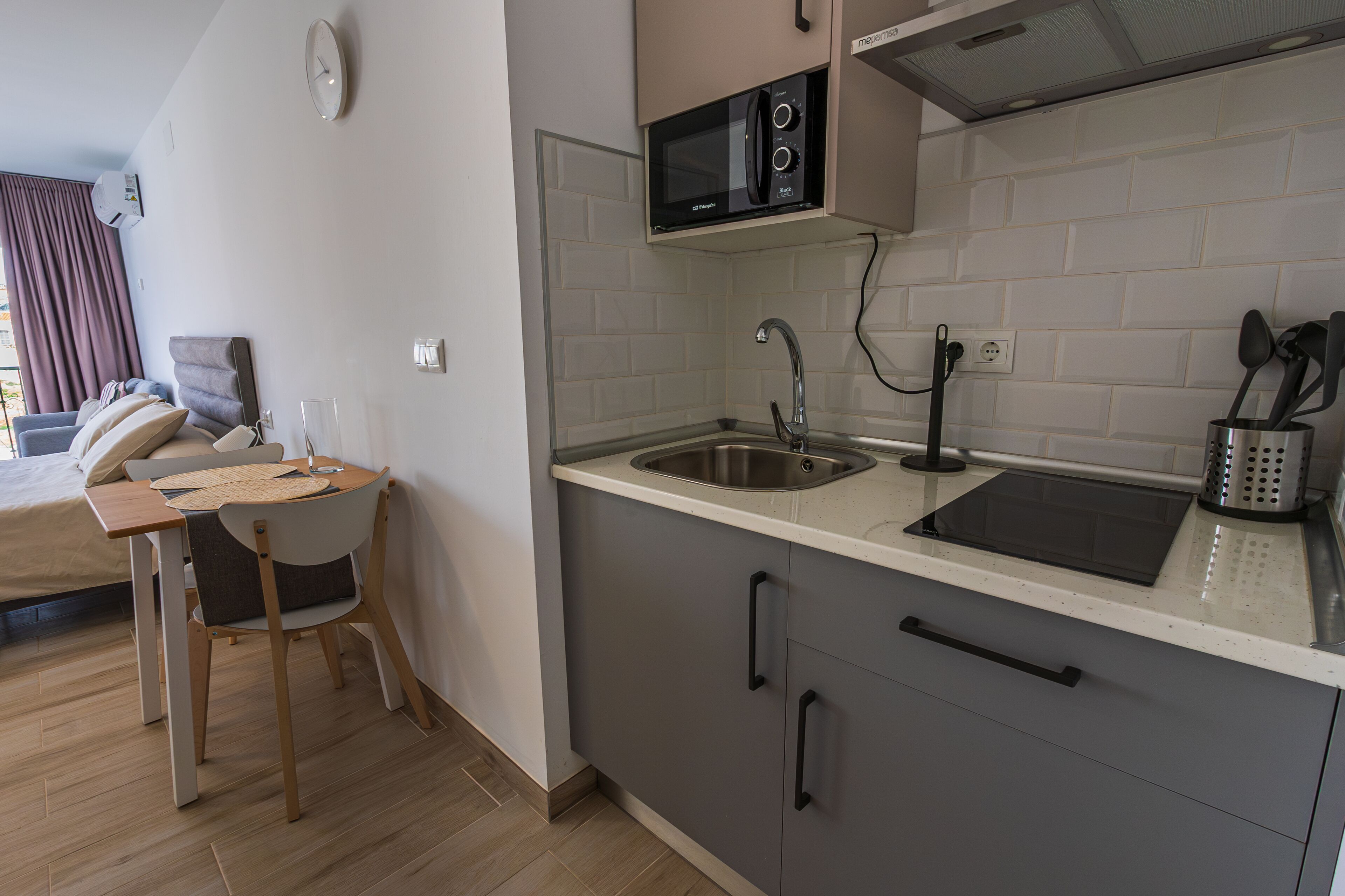 A modern kitchen with a microwave, sink, and a dining area with a table and chairs.
