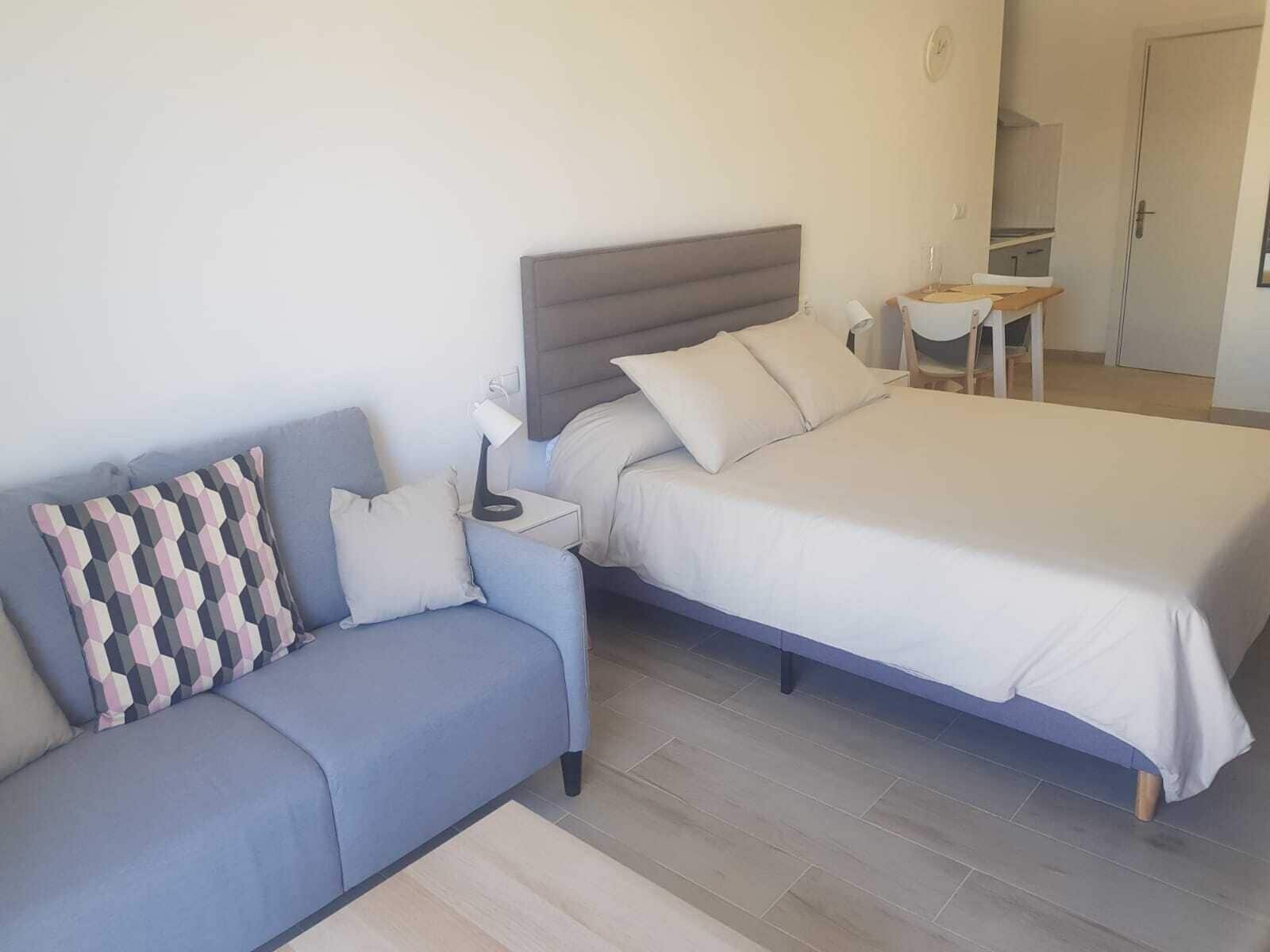 A bedroom with a bed, a sofa, a nightstand, and a desk.