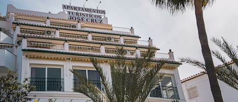 A multi-story building with balconies and a sign that reads "Apartamentos Turísticos José Cruz".