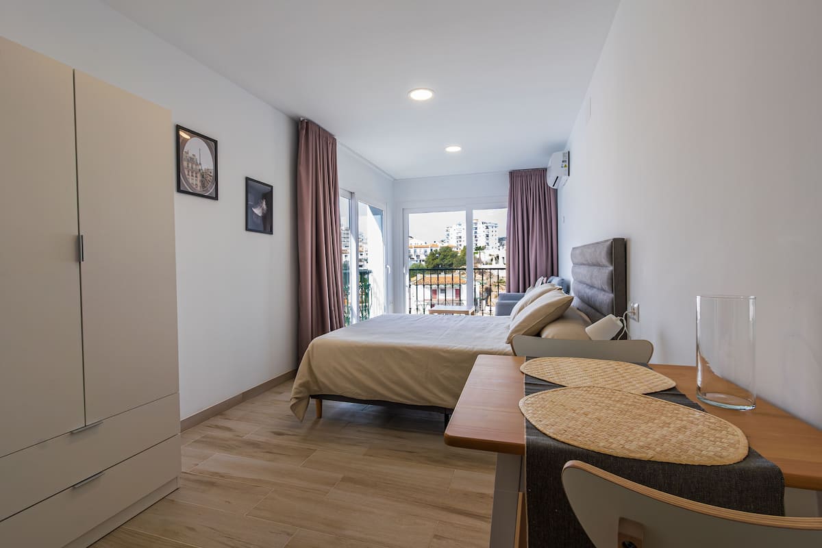A modern hotel room with a bed, a desk, and a view of the city.
