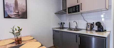Una cocina moderna con un refrigerador de acero inoxidable, un microondas y una tetera sobre la encimera.