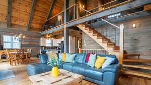 A spacious living area with a blue leather sofa, wooden coffee table, and a staircase leading to an upper level.