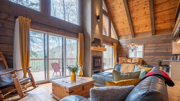 A cozy log cabin interior with a leather sofa, rocking chair, and a fireplace.