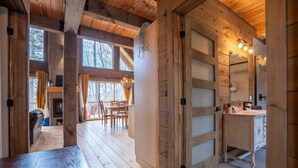 A wooden interior with a dining area, a kitchen, and a large window.