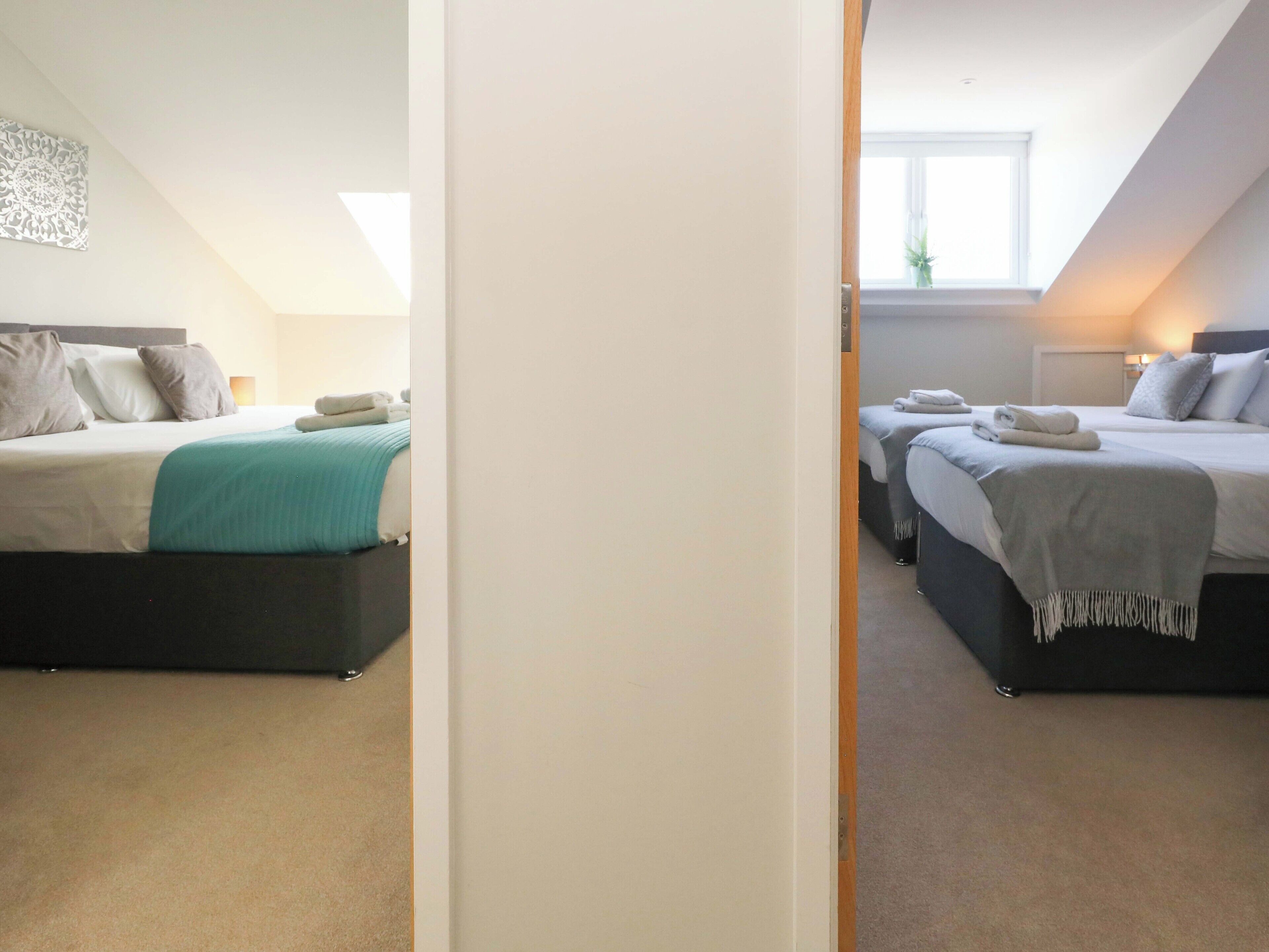 Una camera da letto moderna con un letto grande, un letto più piccolo e una scrivania.