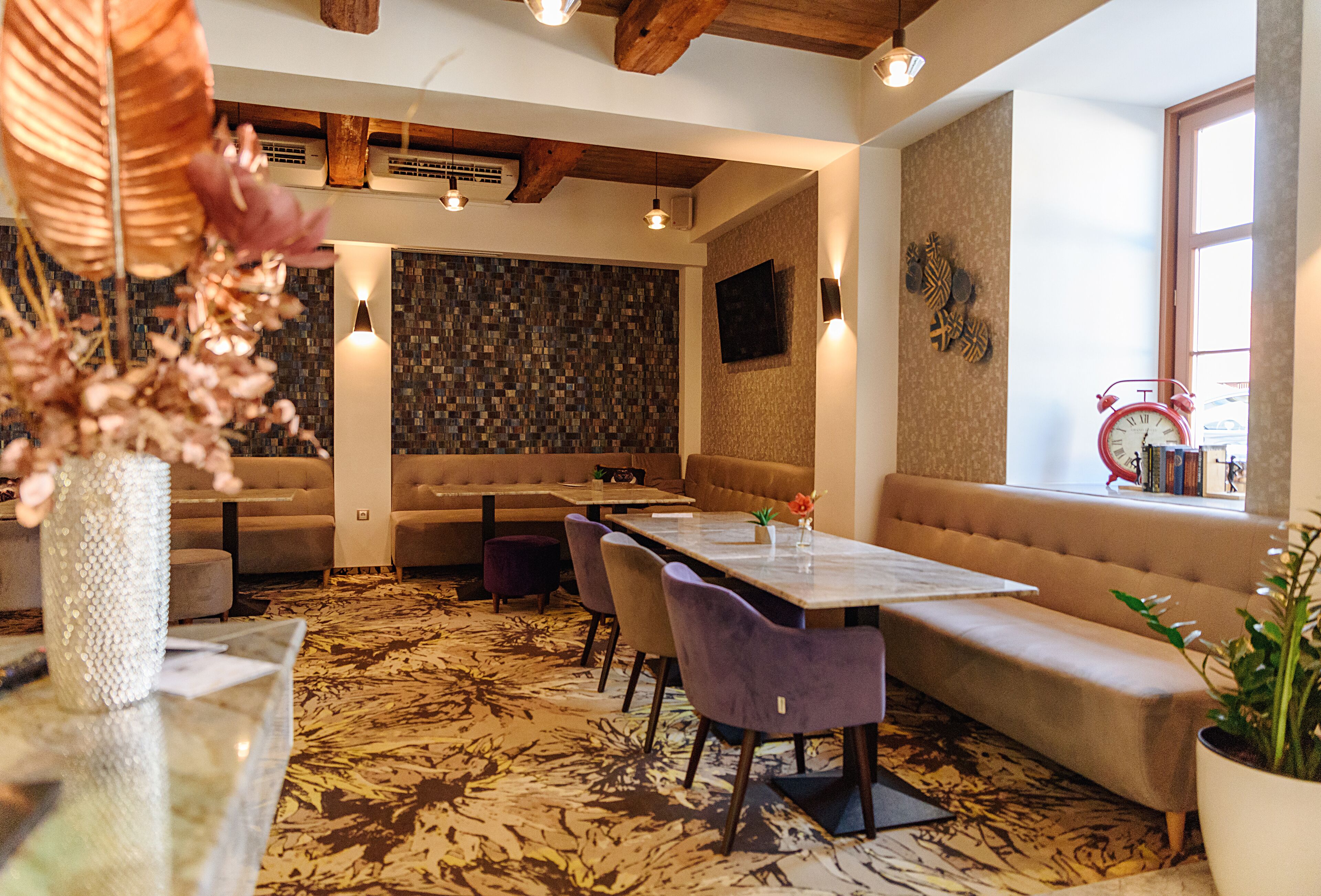 A modern interior with a dining area, sofas, and a patterned carpet.