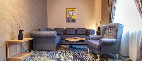 A modern living room with a sectional sofa, a tufted armchair, a coffee table, and a decorative vase.