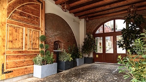 A cobblestone courtyard with a wooden door, brick walls, and potted plants. - ART HOTEL (Sibiu)
