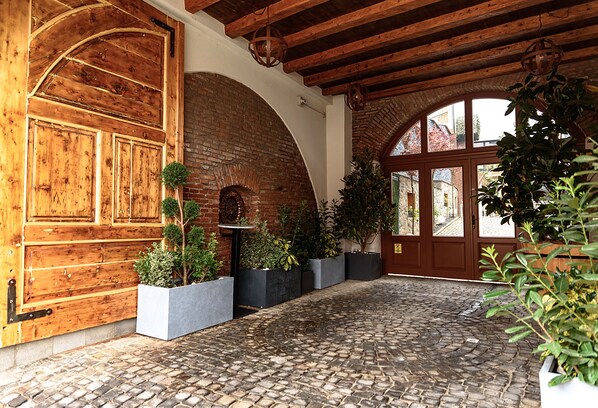 A cobblestone courtyard with a wooden door, brick walls, and potted plants. - ART HOTEL (Sibiu)