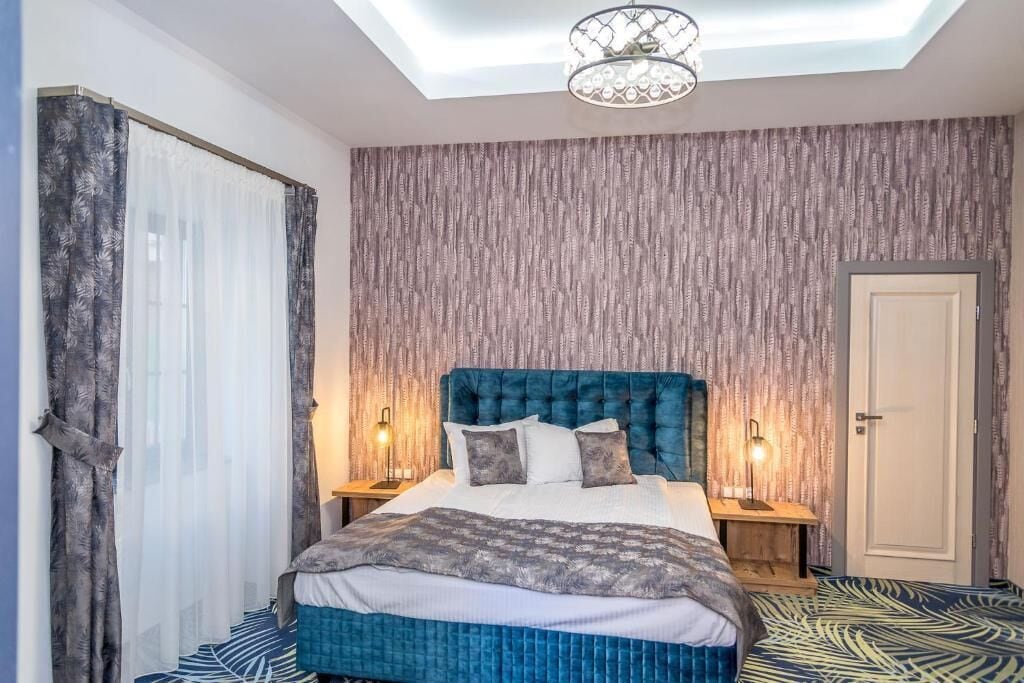 A bedroom with a large bed, two bedside lamps, a ceiling light, and a patterned floor.