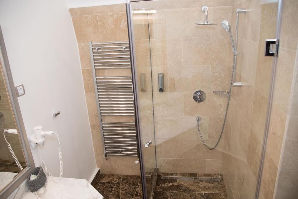 A modern bathroom with a glass-enclosed shower, a towel rack, and a marble countertop.