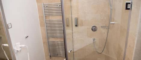 A modern bathroom with a glass-enclosed shower, a towel rack, and a marble countertop.