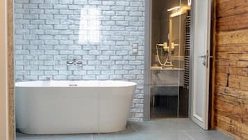 A modern bathroom with a freestanding bathtub, a glass shower enclosure, and a wooden wall.