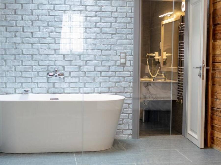 A modern bathroom with a freestanding bathtub, a glass shower enclosure, and a wooden wall.