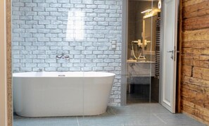 A modern bathroom with a freestanding bathtub, a glass shower enclosure, and a wooden wall. - ART HOTEL (Sibiu)