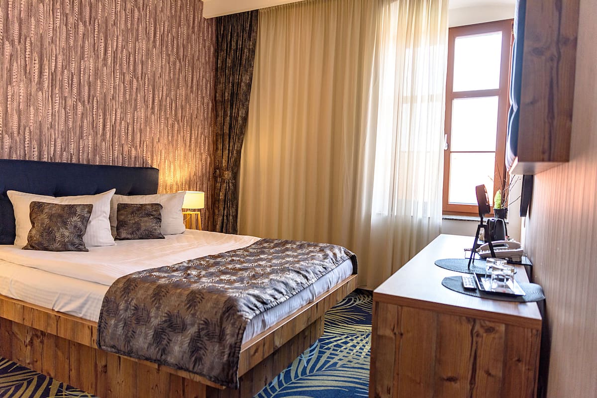 A hotel room with a bed, a desk, and a window.