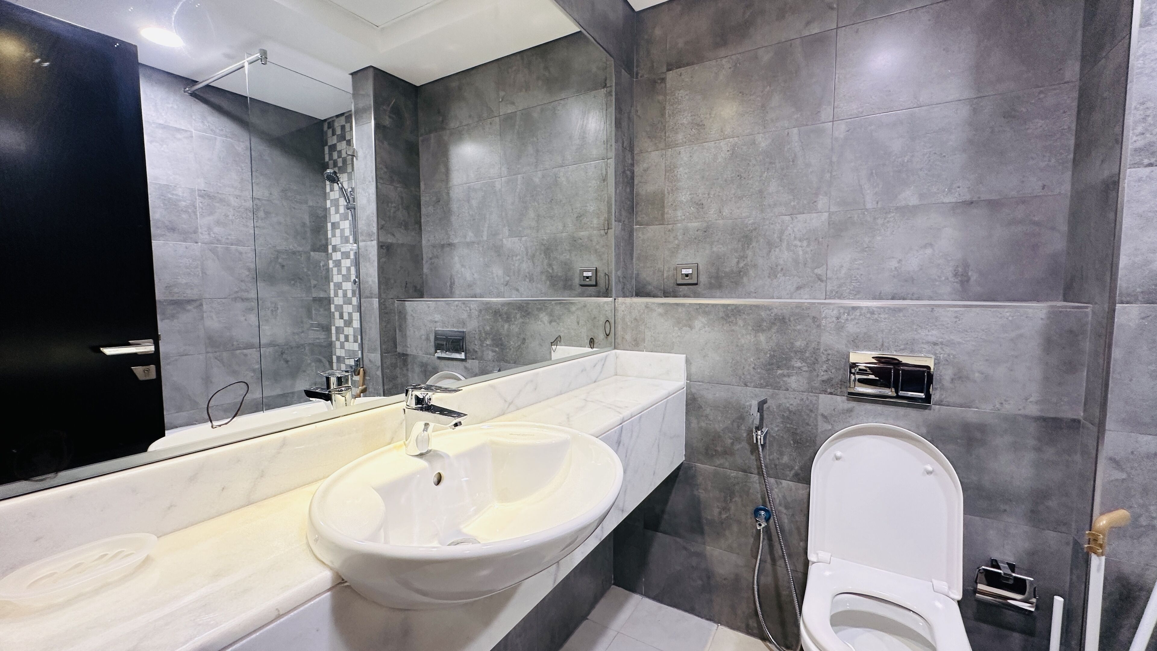 Ein modernes Badezimmer mit einem großen Spiegel, einem weißen Waschbecken, einer Badewanne und einer Toilette.