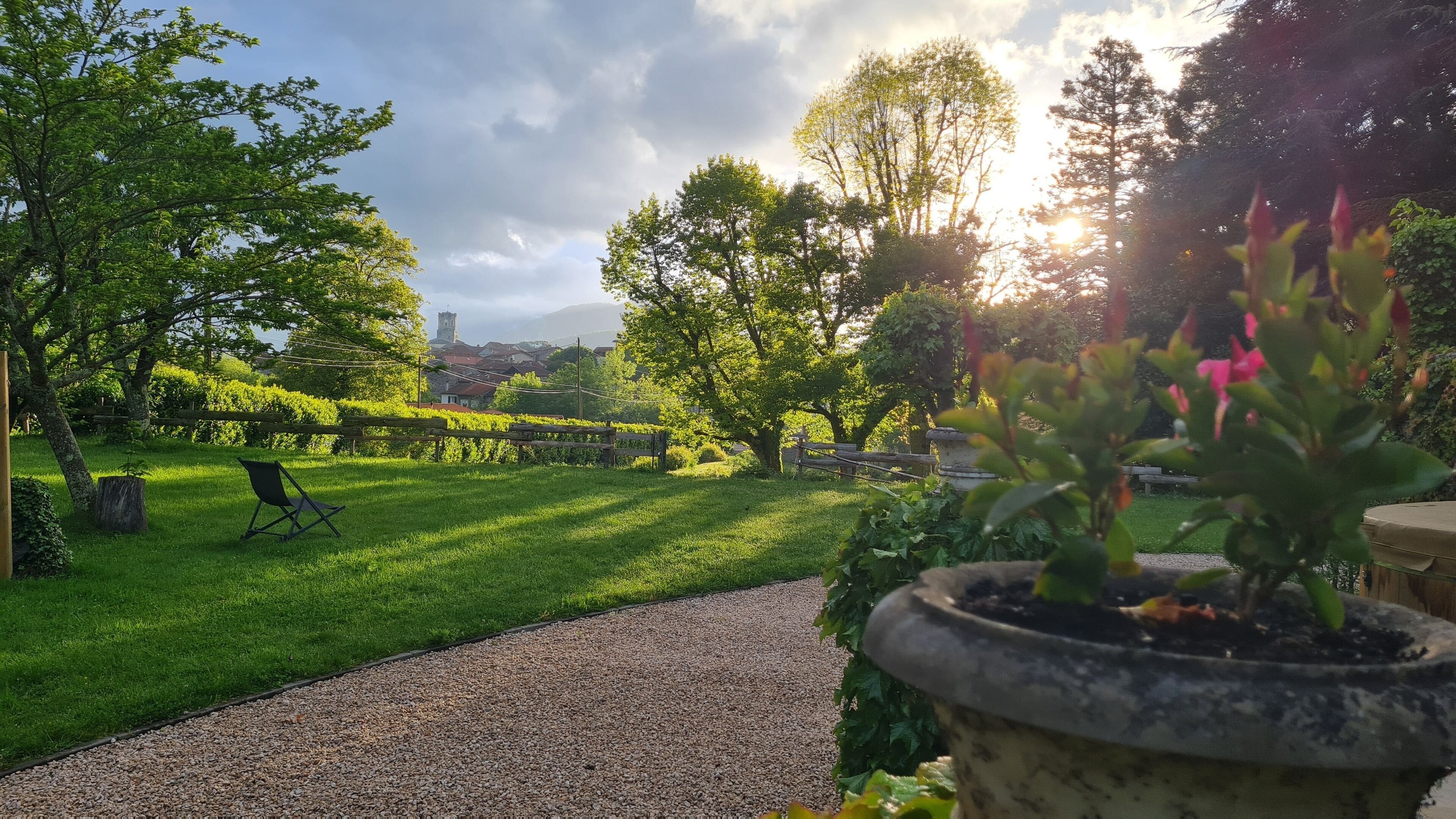 A garden with a gravel path, wooden fence, and a bench.