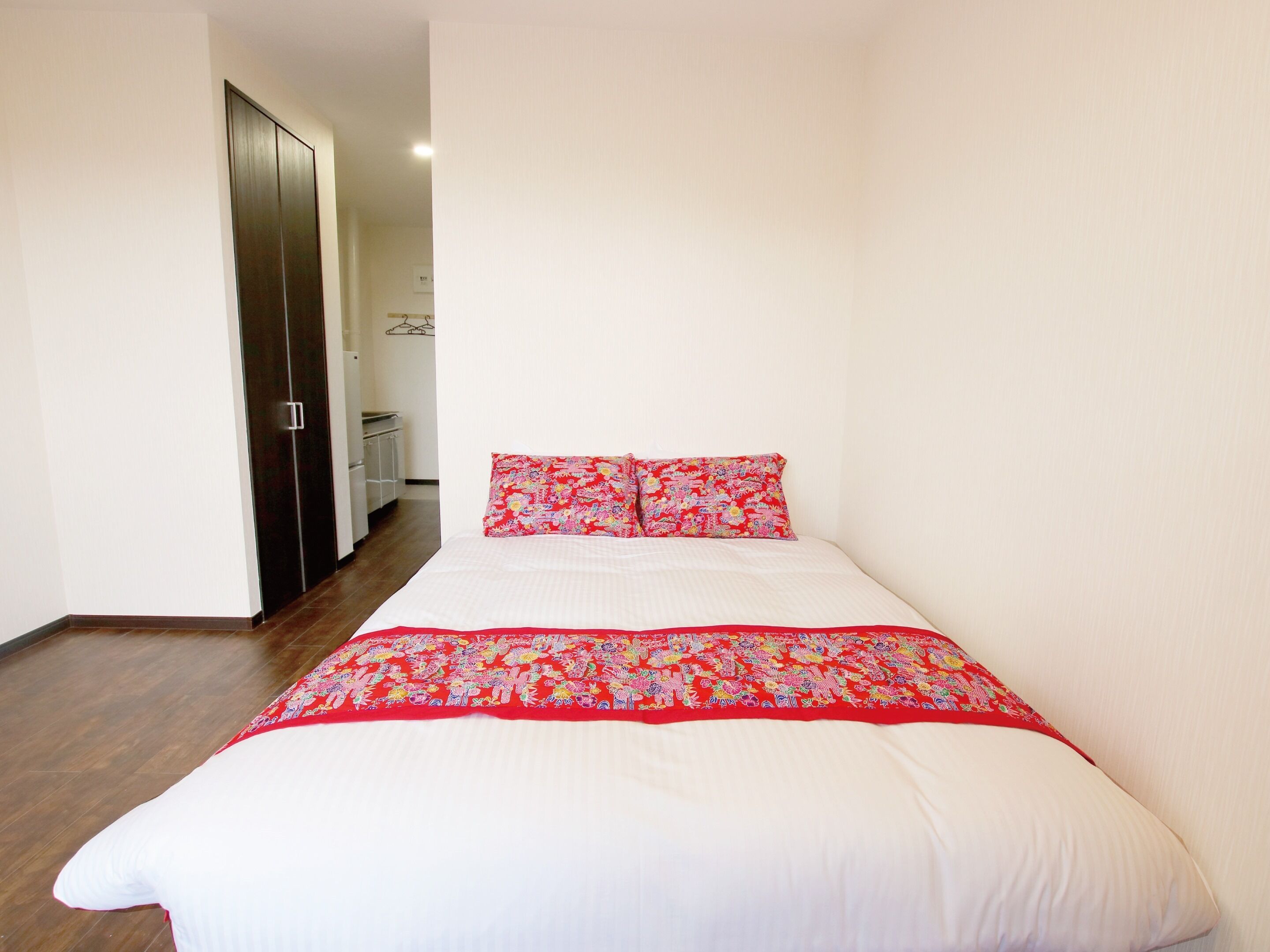 Une chambre à coucher avec un lit, une armoire et, au fond, une petite kitchenette.