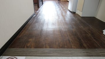 A hallway with wooden flooring, a sign on the floor, and a door leading to another room.