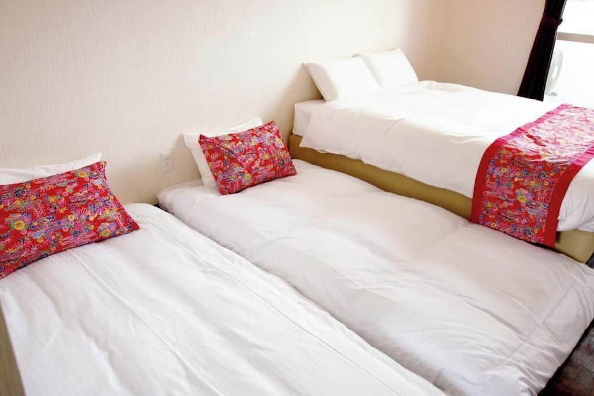 A hotel room with two beds, each with white bedding and colorful floral pillows.