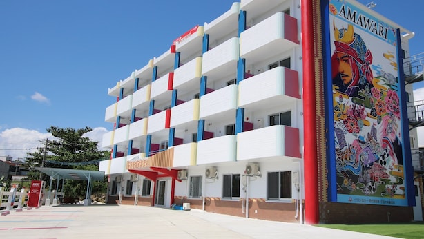 Un hotel de varios pisos con balcones coloridos y un gran mural en la fachada.