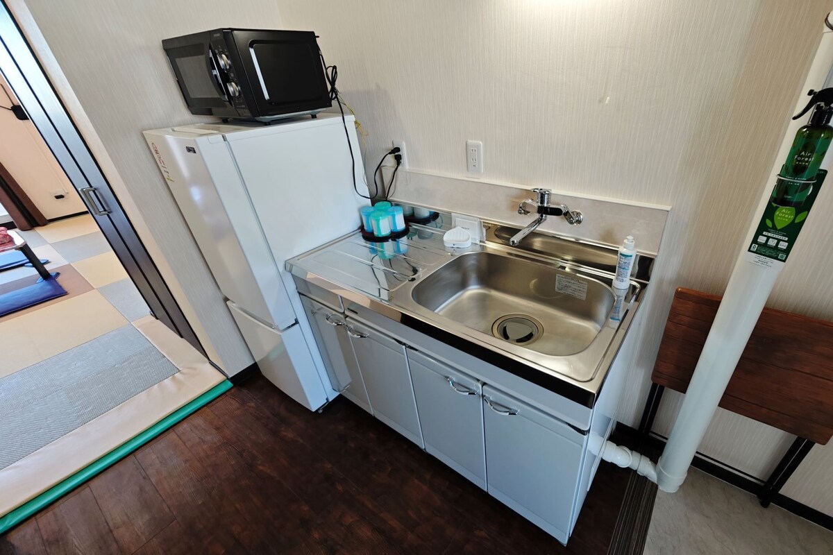 Une petite cuisine équipée d’un four à micro-ondes, d’un réfrigérateur, d’un évier et d’un petit placard.