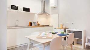 A modern kitchen with white cabinetry, a built-in oven, a microwave, and a coffee machine. - il Nespolo (Bologna)