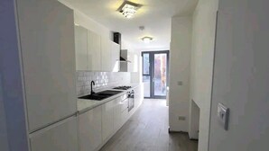 A modern kitchen with white cabinets, a black sink, and a stove. - Apartment - Sleeps up to 6 & Free Parking (London)